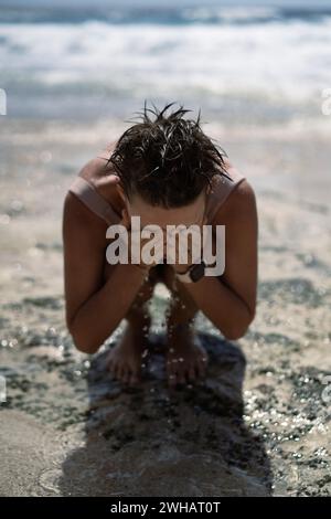 Una giovane donna si bagna nell'oceano e bagna l'acqua salata, in vacanza al mare Foto Stock