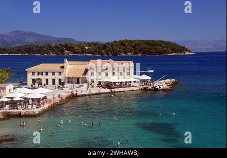 Persone che nuotano e prendono il sole nei bar e Trevena sulla spiaggia di Faliraki (spiaggia di Alekos) a Corfù, Grecia, UE. Foto Stock