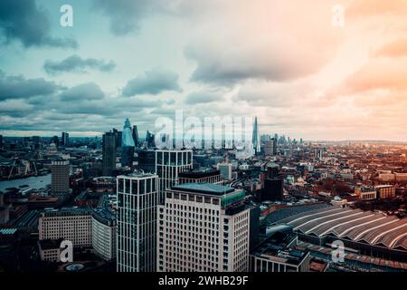 Spettacolare prospettiva aerea dello skyline di Londra, catturando il contrasto tra strutture storiche e moderni grattacieli sotto una vasta striscia di nuvole Foto Stock