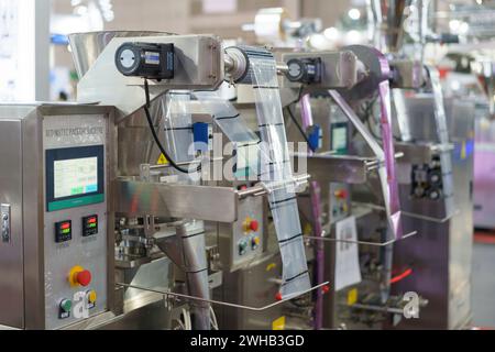 Un'avanzata macchina per il confezionamento automatico funziona con precisione, con un rotolo di pellicola e un pannello di controllo touch screen, essenziale per l'alta velocità moderna Foto Stock