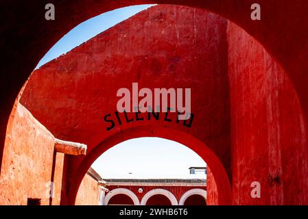 Silenzio scritto sul muro rosso e sull'arco nella città Inca di Cuzco in Perù Foto Stock