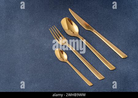 Set di posate in metallo dorato. Forchetta, cucchiaio, coltello, cucchiaino Foto Stock