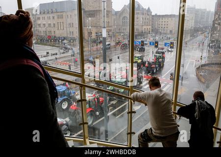 Poznan, Polonia, 9 febbraio 2024. La gente guarda come gli agricoltori della grande Polonia nella Polonia occidentale guidano i loro trattori mentre bloccano la strada Aleja Niepodleglosci nel centro di Poznań, la capitale della grande Polonia durante lo sciopero degli agricoltori a livello nazionale. La protesta in Polonia fa parte della protesta degli agricoltori europei contro i regolamenti del Green Deal dell'UE. Gli agricoltori polacchi chiedono inoltre una modifica dell'accordo UE con l'Ucraina in merito all'importazione di prodotti agricoli nell'UE. La protesta a Poznań, la capitale della grande Polonia, fu organizzata da Rola Wielkopolska e si riunì Foto Stock