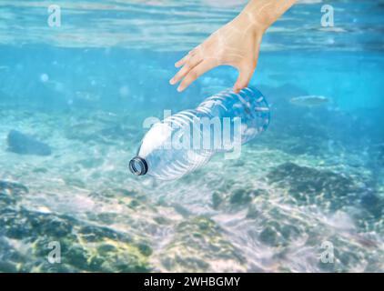 Uomo che raccoglie a mano una bottiglia di plastica dell'oceano con spazio per le copie Foto Stock