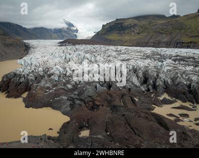 Ghiacciaio Svinafellsjokull in Islanda in una giornata nuvolosa, formazioni di ghiaccio uniche circondate da montagne, e una laguna glaciale, vista aerea. Natura e. Foto Stock