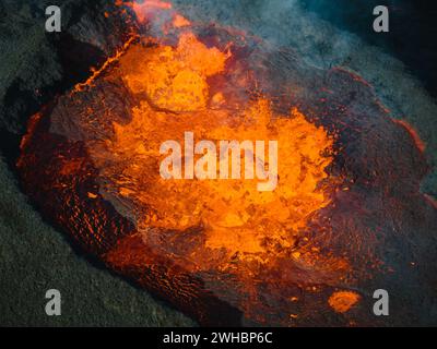 Vista spettacolare del buio paesaggio vulcanico con la lava che si scioglie che bolle nel cratere, vulcano attivo durante l'eruzione in Islanda, colpo aereo. Foto Stock