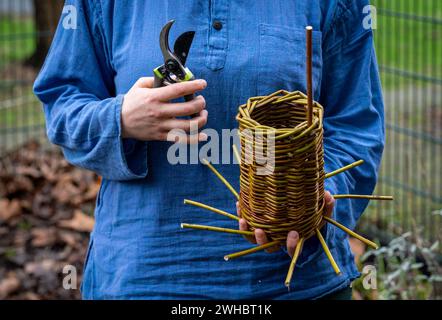 Artigiana che produce casette per uccelli intrecciate, cesto di vimini con rami di salice Foto Stock