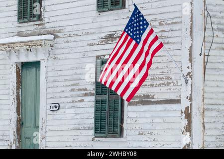 Una bandiera americana è esposta sul lato di un'antica casa nel quartiere storico di Elm Hill Farm a Brookfield, Massachusetts, Stati Uniti. Foto Stock