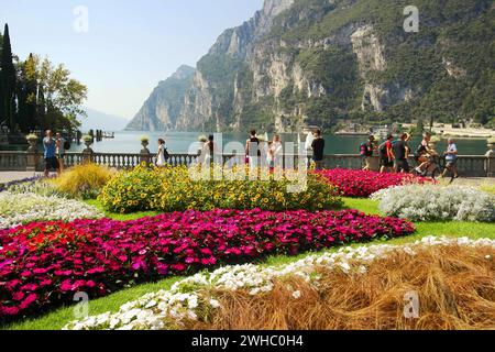 Vista sul Lago di Garda con splendidi fiori e turisti. 15 agosto 2023 Riva del Garda, Italia ​ Foto Stock