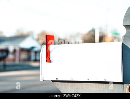 Cassetta postale bianca con la bandiera rossa in alto su una strada rurale Foto Stock