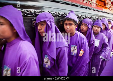 Antigua, Guatemala. Ragazzi adolescenti che portano un float in una processione religiosa durante la settimana Santa, la Semana Santa. Foto Stock
