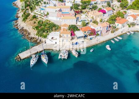 Assos pittoresco villaggio di pescatori dall'alto, Cefalonia, Grecia. Vista aerea del drone. Barche a vela ormeggiate nella baia turchese. Foto Stock