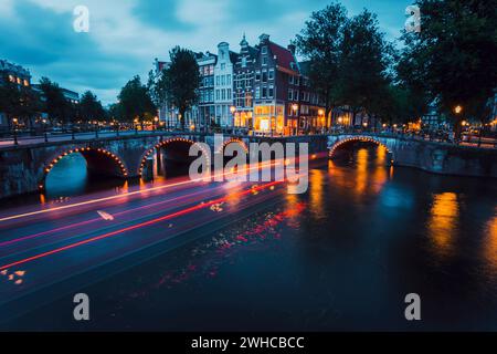 Incredibili percorsi leggeri e riflessi sull'acqua ai canali Leidsegracht e Keizersgracht di Amsterdam di sera. Scatto con esposizione lunga. concetto di viaggio romantico in città. Foto Stock