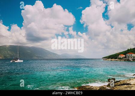 Yacht bianco che va in mare aperto sotto un incredibile paesaggio bianco senza fine. Acqua cristallina e trasparente turchese di fronte alla città di Fiskardo. Cefalonia, isole Ionie, Grecia. Foto Stock