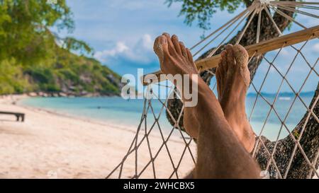 Uomini a piedi in un'amaca, rilassarsi sulla spiaggia di Haad Rin, Ko Phangan. Thailandia Foto Stock