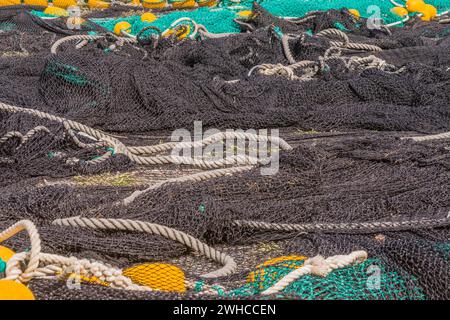 Primo piano di grandi reti da pesca nere e verdi con galleggianti gialli disposti a terra per asciugare in Corea del Sud Foto Stock