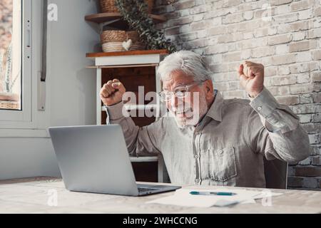 Felice, eccitato, vecchio anziano vincitore eccitato leggendo buone notizie guardando il notebook, felicissimo nonno anziano maturo che guarda la partita online celebrando goal Bid bet vincere grande risultato concetto di vittoria Foto Stock