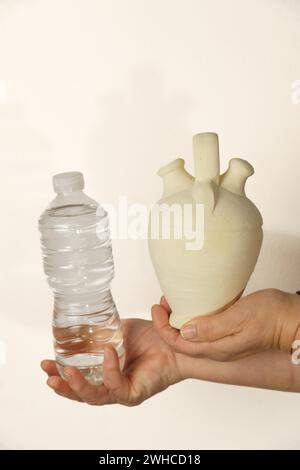 Donna che tiene in mano una caraffa in terracotta e una bottiglia di plastica, concetto di uso sostenibile della plastica Foto Stock