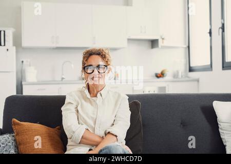 Foto della testa di una donna sorridente che fa videochiamate ad amici o parenti, usando la webcam, seduto sul divano di casa, giovane blogger felice che registra vlog, guarda la fotocamera, chatta online Foto Stock