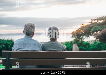 Foto della testa Ritratto da vicino donna di mezza età con i capelli grigi felice con marito più grande, godendosi seduto sulla panchina al parco. Una vecchia coppia di famiglie che abbraccia e guarda il tramonto. Foto Stock