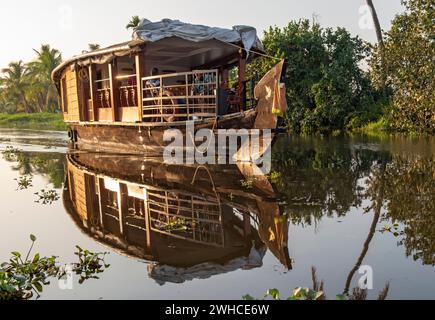 Una tradizionale casa galleggiante naviga lungo i canali vicino a Kumarakom, offrendo un modo unico di esplorare le tranquille backwaters del Kerala, in India Foto Stock