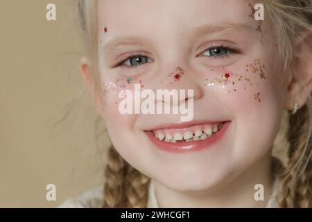 Ritratto di una bambina bionda con occhi blu e scintillanti sul viso. Foto Stock