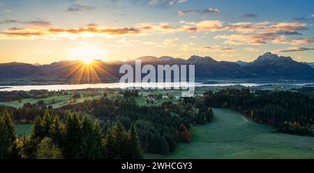 Alba sul Forggensee vicino a Füssen. Alpi Ammergau innevate sullo sfondo. Baviera, Germania, Europa Foto Stock