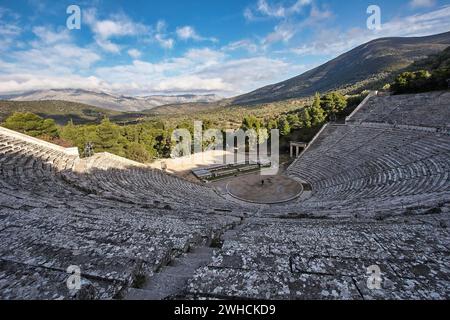 Vista panoramica di un antico anfiteatro sullo sfondo di una montagna sotto un cielo parzialmente nuvoloso, Anfiteatro Antico, Epidauro, Peloponneso, Grecia Foto Stock