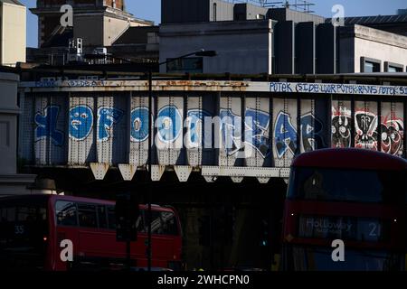 Il traffico serale dell'ora di punta passa sotto una ferrovia graffeggiata vicino alla stazione di London Bridge. Borough High Street, Londra, Regno Unito. 7 giugno 2023 Foto Stock