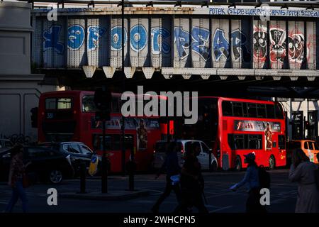 Il traffico serale dell'ora di punta passa sotto una ferrovia graffeggiata vicino alla stazione di London Bridge. Borough High Street, Londra, Regno Unito. 7 giugno 2023 Foto Stock
