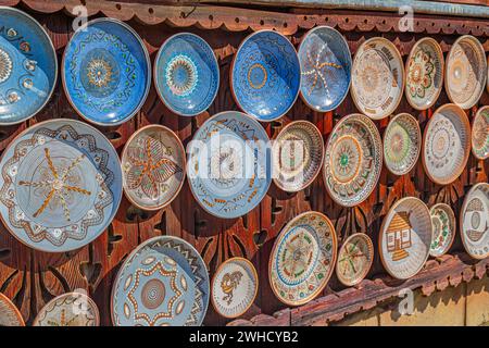 Piatti in ceramica tradizionale rumena della zona di Horezu, Romania, adagiati ornamentali su una rustica parete di legno in casa. Foto Stock