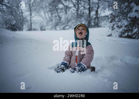 Bambina che gioca nel mezzo della foresta su una superficie innevata Foto Stock