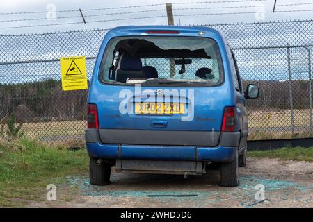 Concetto di criminalità automobilistica: Un'auto con un parabrezza posteriore rotto nonostante sia parcheggiata accanto a un segnale di CCTV nelle telecamere di funzionamento Foto Stock