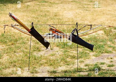 Due archi di legno con frecce sullo sfondo dei bersagli. Una gara di tiro con l'arco. Arma per sparare frecce. Coppia tiro con l'arco Foto Stock