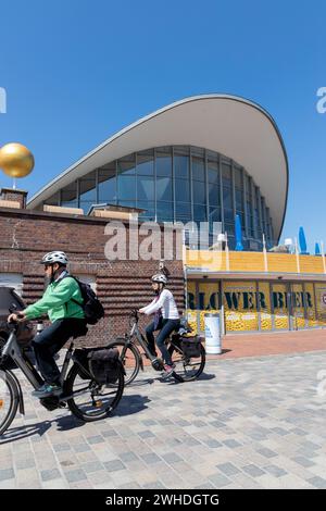 I punti di riferimento della sfera d'oro del Planet Trail e Teepott dal retro e ciclista in primo piano in strada a Warnemünde, città anseatica di Rostock, costa del Mar Baltico, Meclemburgo-Pomerania occidentale, Germania, Europa Foto Stock