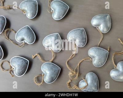 I ciondoli decorativi in argento a forma di cuore si trovano su uno sfondo grigio per festeggiare l'amore a San Valentino Foto Stock