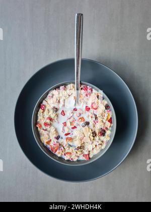 Muesli con latte in una ciotola per colazione, muesli di frutta con cereali e frutta, cucchiaio Foto Stock