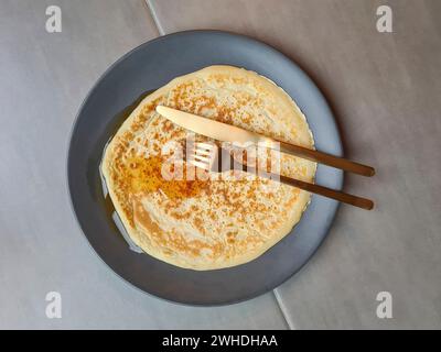 Frittelle su un piatto grigio con posate dorate, piatto a base di uova con coltello e forchetta Foto Stock