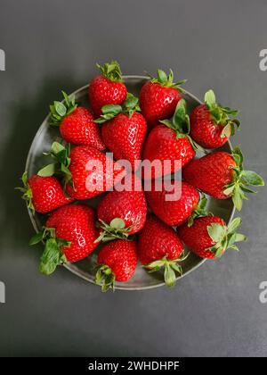 Fragole rosse fresche in un recipiente su sfondo grigio Foto Stock