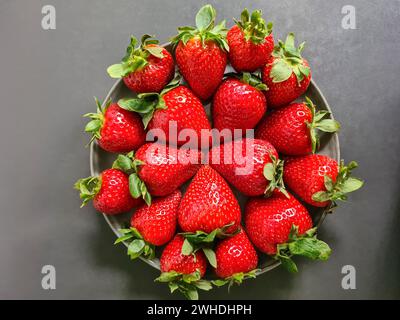 Fragole rosse fresche in un recipiente su sfondo grigio Foto Stock