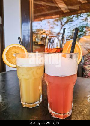 Due cocktail analcolici in un bicchiere con una fetta di arancia e paglia in primo piano su un tavolo Foto Stock