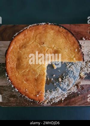 Un quarto della cheesecake rotonda manca dal fondo del piatto da forno, servito fresco Foto Stock