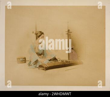 Donna giapponese, a tutta lunghezza, seduta, rivolta a destra, che gioca un koto; uno shamisen si appoggia contro un muro sullo sfondo....Giappone colorato a mano con watercolor Photographic Print intorno agli anni '1870 Foto Stock