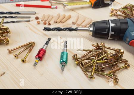 Lavorazione del legno, utensili per la posa di tasselli in legno, vari strumenti di misurazione, fissacavi, trapano per legno, matita, metro a nastro, viti per legno Torx, trapano a batteria, fondo in legno, Foto Stock