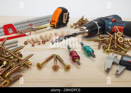 Lavorazione del legno, utensili per la posa di tasselli in legno, vari strumenti di misurazione, fissacavi, trapano per legno, matita, metro a nastro, viti per legno Torx, trapano a batteria, fondo in legno, Foto Stock