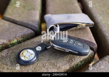 Chiave dell'auto con Apple AirTag lasciato su una panchina del parcheggio, immagine del simbolo, ricerca chiavi, chiave dell'auto dimenticata, Foto Stock