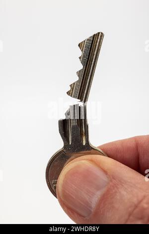 Mano maschio che tiene una chiave aperta per porta, chiave cilindrica, sfondo bianco, Foto Stock