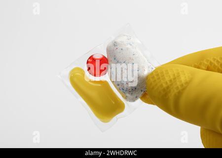 Linguetta per lavastoviglie in foglio solubile in acqua, guanto protettivo giallo, sfondo bianco, Foto Stock