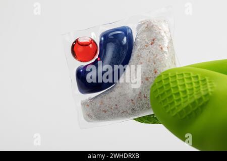 Linguetta per lavastoviglie in foglio solubile in acqua, guanto protettivo verde, sfondo bianco, Foto Stock