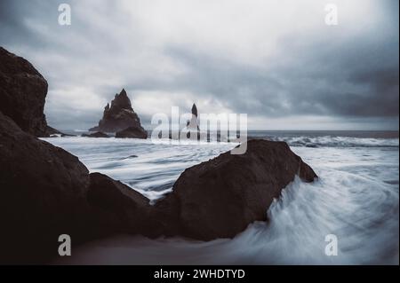 Spiaggia di Reynisfjara in Islanda. Spiaggia di sabbia nera con formazioni basaltiche. Esposizione lunga con onde. Foto Stock